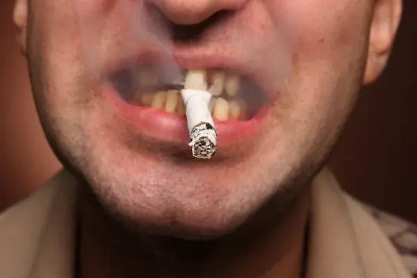 persona fumando con cáncer oral