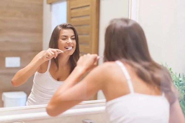 mujer cepillandose los dientes de una sonrisa sana