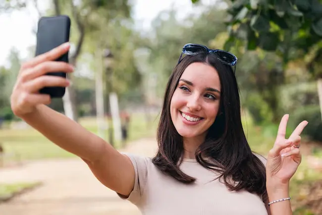 Persona sonriendo feliz mientras toma una selfie para compartir frases odontológicas en redes